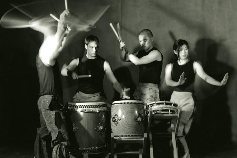 Members of On Ensemble gather around playing three drums